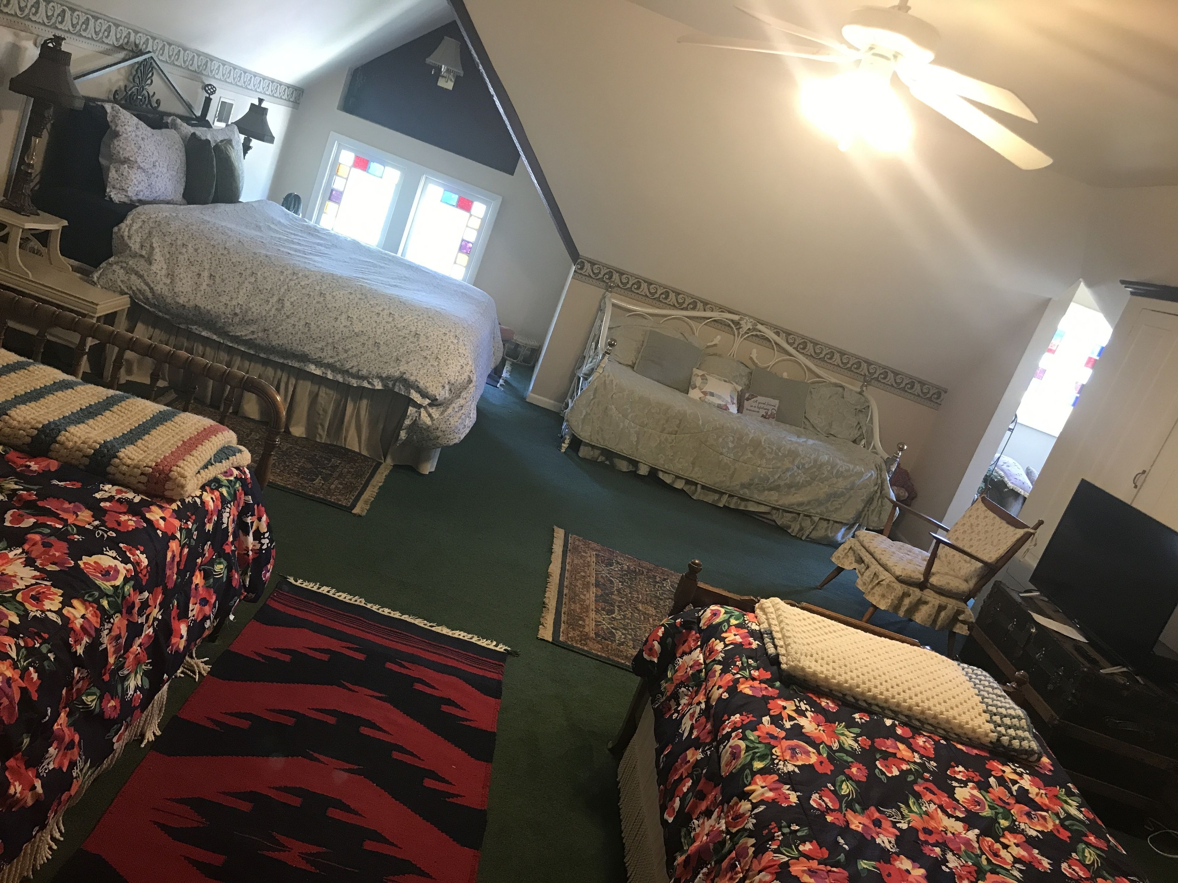 A bedroom with two beds, a ceiling fan, and a television.