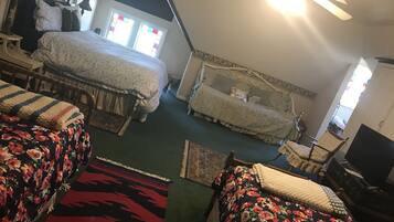 A bedroom with two beds, a ceiling fan, and a television.