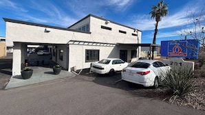 Il s’agit d’un immeuble à deux étages, avec un espace de stationnement situé à l’avant. Deux voitures blanches sont garées sur le parking.