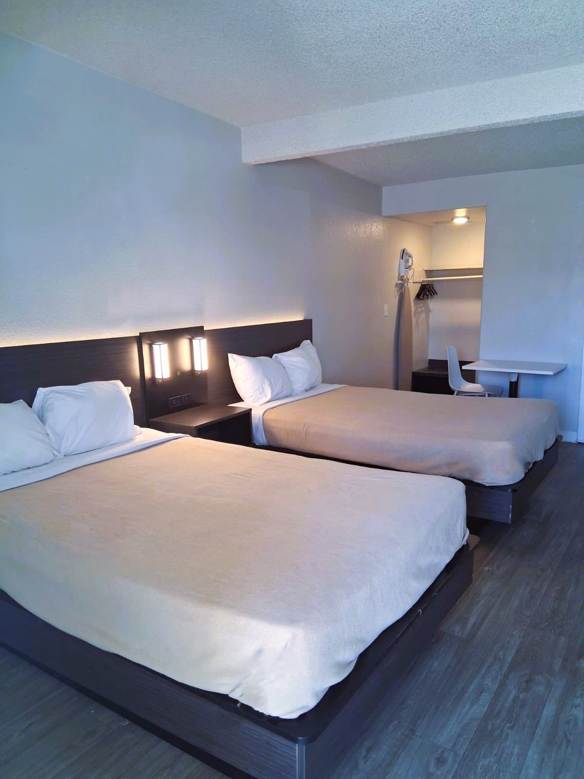 Habitación de hotel con dos camas, un escritorio y zona de ducha.
