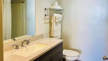 A bathroom with a double sink, a toilet, a towel rack, and a mirror.