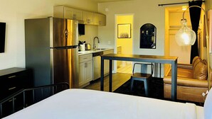 Une chambre d’hôtel compacte comprenant un lit, une kitchenette et un coin salon.