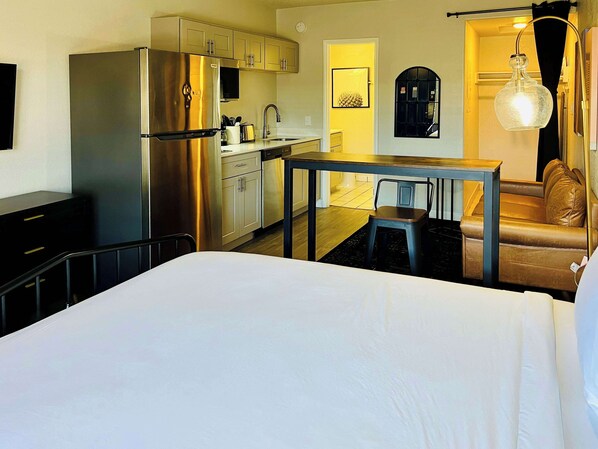 Une chambre d’hôtel compacte comprenant un lit, une kitchenette et un coin salon.