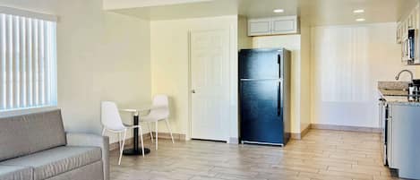 A modern kitchen with a built-in refrigerator, white cabinets, and a dining area with a table and chairs.