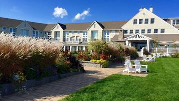 A hotel with a covered outdoor area, a pathway, and a lawn with chairs.