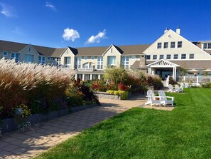 A hotel with a covered outdoor area, a pathway, and a lawn with chairs.