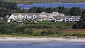 A large, multi-story resort with a central building and several wings, situated near a beach and a lake. - Inn By The Sea (Cape Elizabeth)