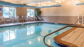 Piscina interior com água cristalina, um deck revestido e algumas cadeiras na lateral.