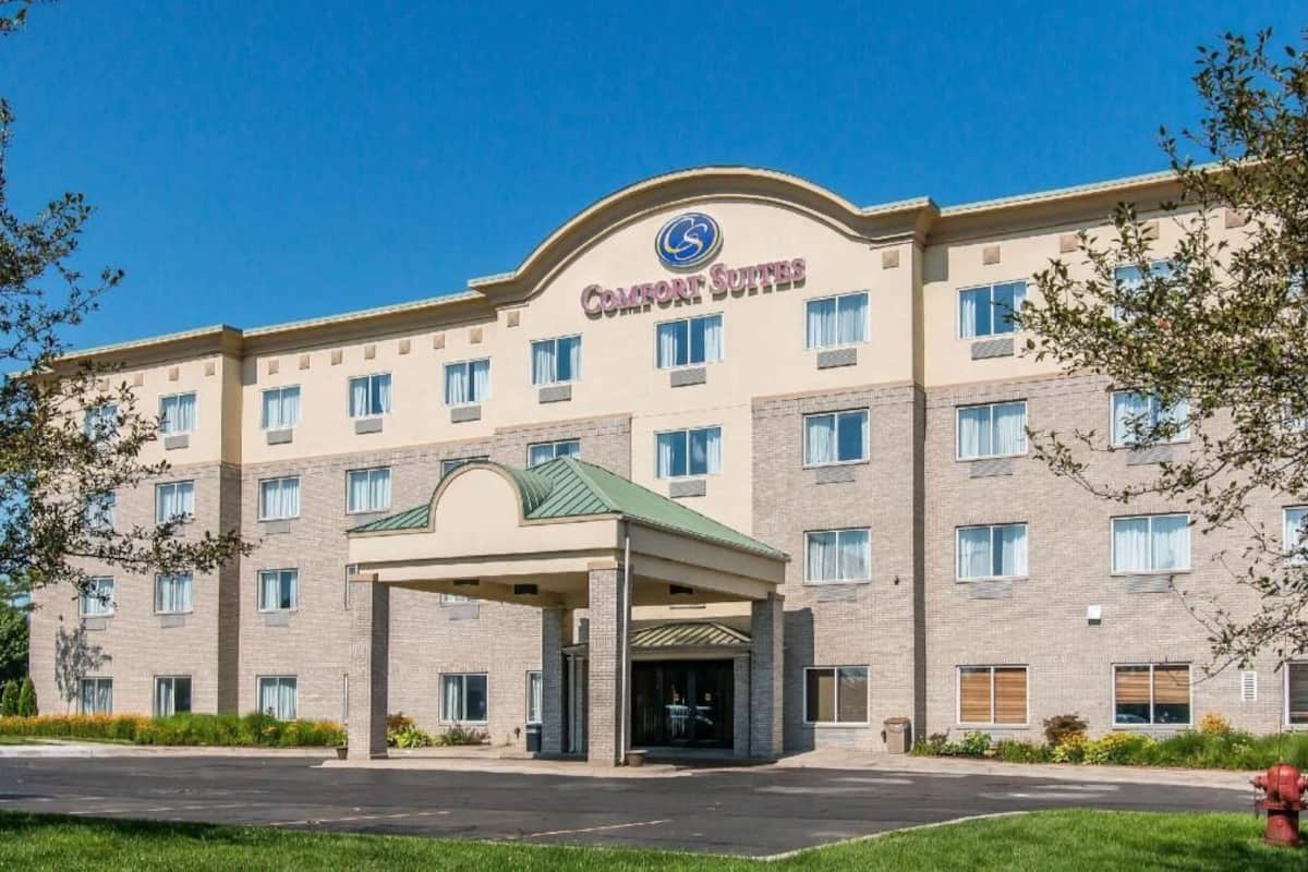 A multi-story hotel with a prominent entrance, a covered area, and a clear sky.