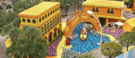 A courtyard with a yellow building, a bridge, and a fountain.