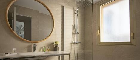 A modern bathroom with a large round mirror, a shower with a rain showerhead, and a frosted glass window.