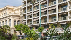 A multi-story hotel with balconies, a well-maintained lawn, and parked cars. - Hotel Chambord (Menton)