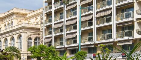 A multi-story hotel with balconies, a well-maintained lawn, and parked cars.