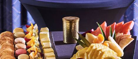 A dessert table with various pastries, fruits, and a decorative vase.