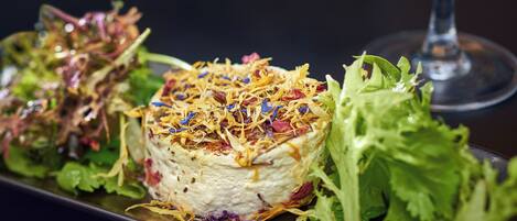 A plated dish with a variety of greens and shredded toppings, accompanied by a glass of wine.