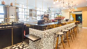 Una zona de bar moderna con una barra larga, taburetes y una máquina de café.
