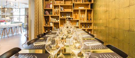 A restaurant with a long table set for a meal, surrounded by shelves of books and wine bottles.