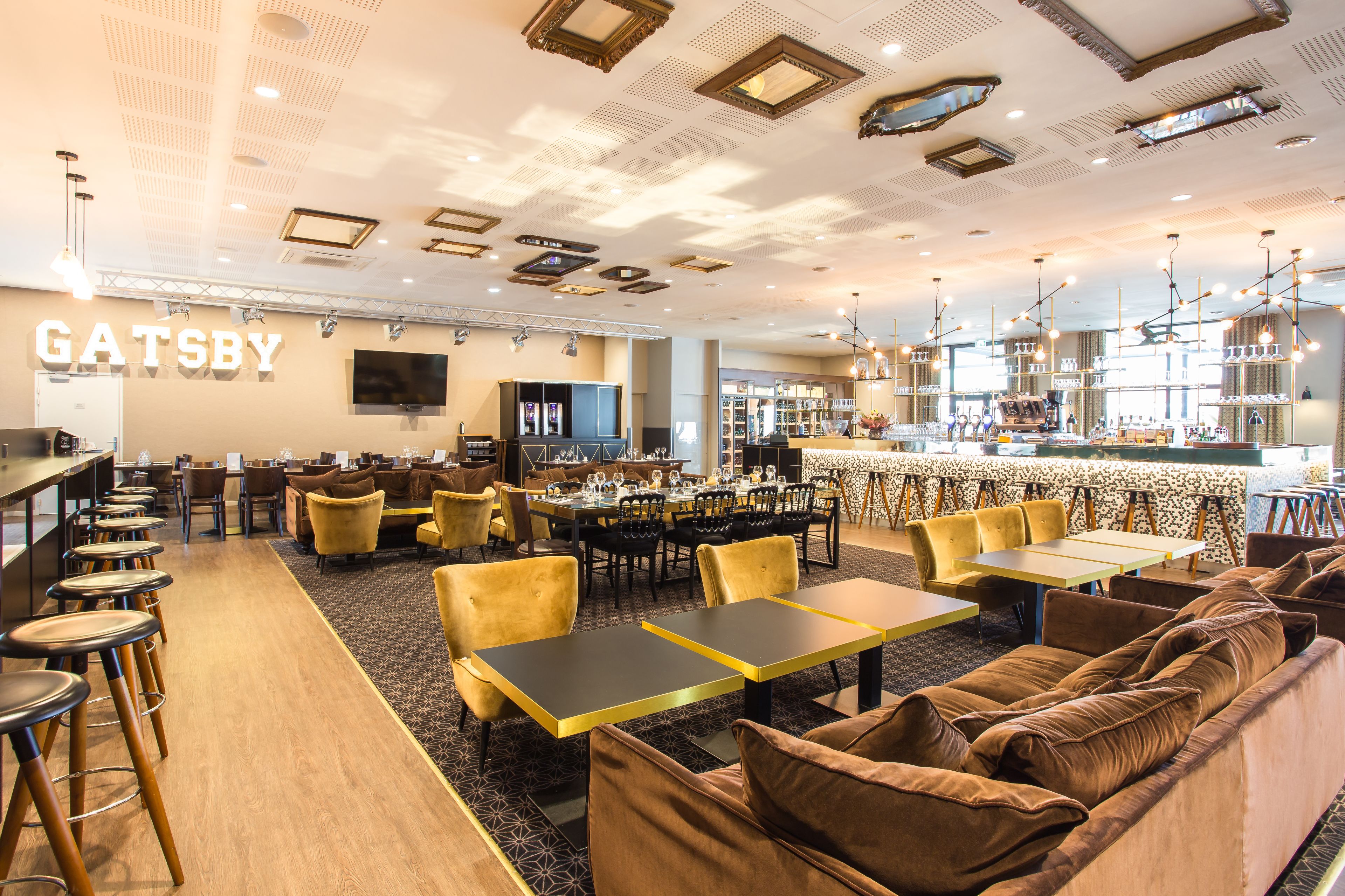 Un restaurante amplio con varias zonas de estar, incluyendo taburetes de bar, mesas y sofás.