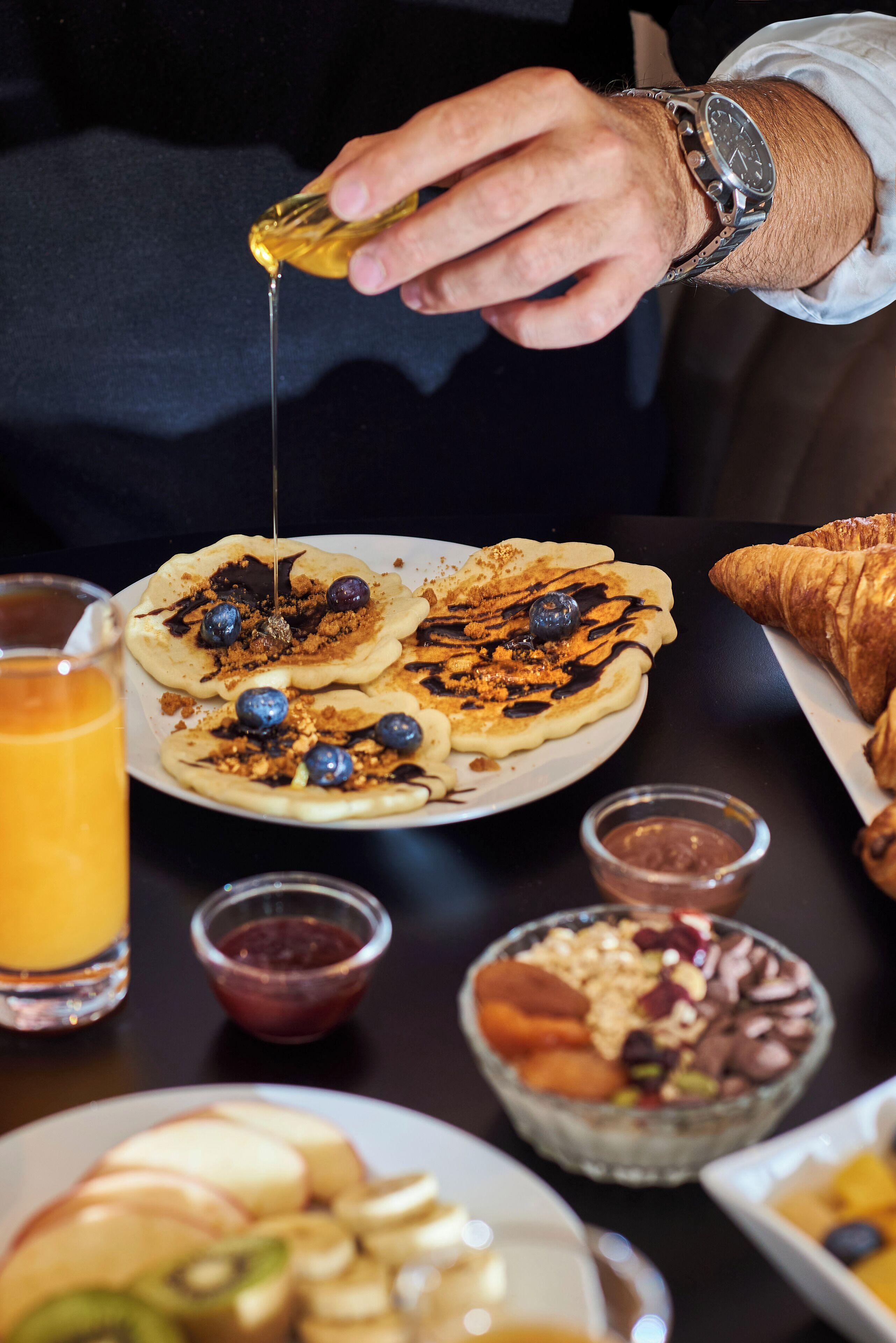 A breakfast setting with pancakes, blueberries, and a croissant.