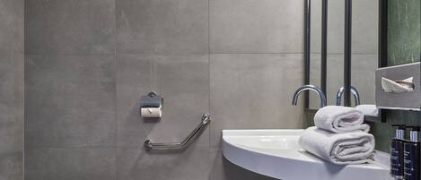 Un baño moderno con inodoro blanco, lavamanos con toallero y barandilla.