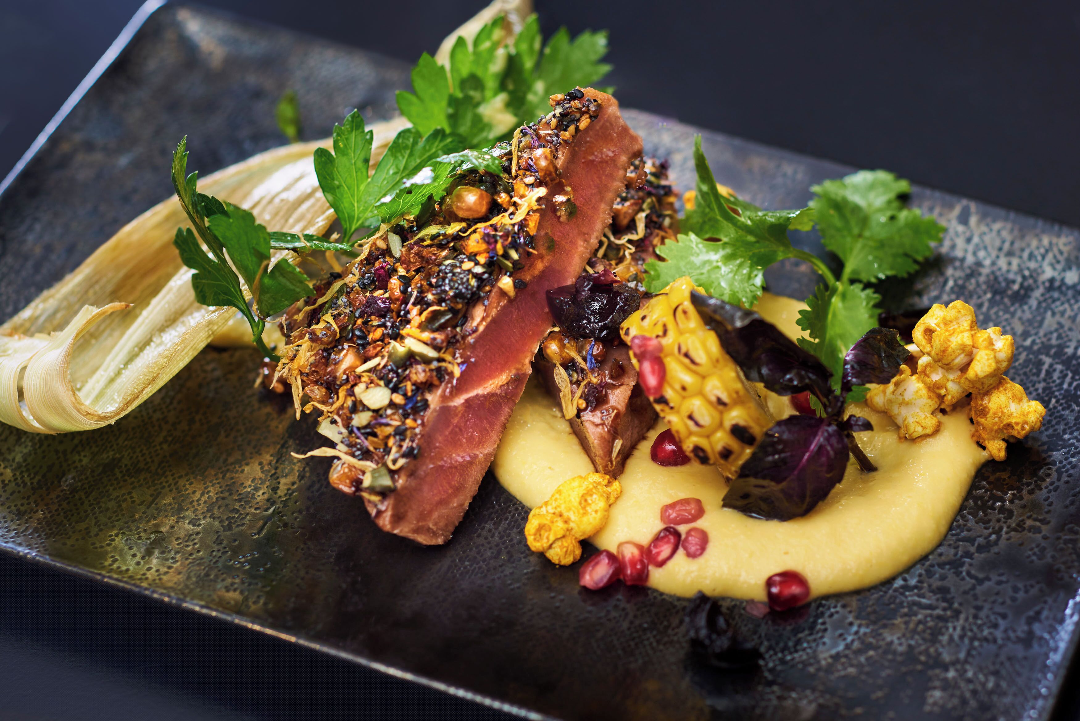 A dish with various ingredients and garnishes on a dark plate.