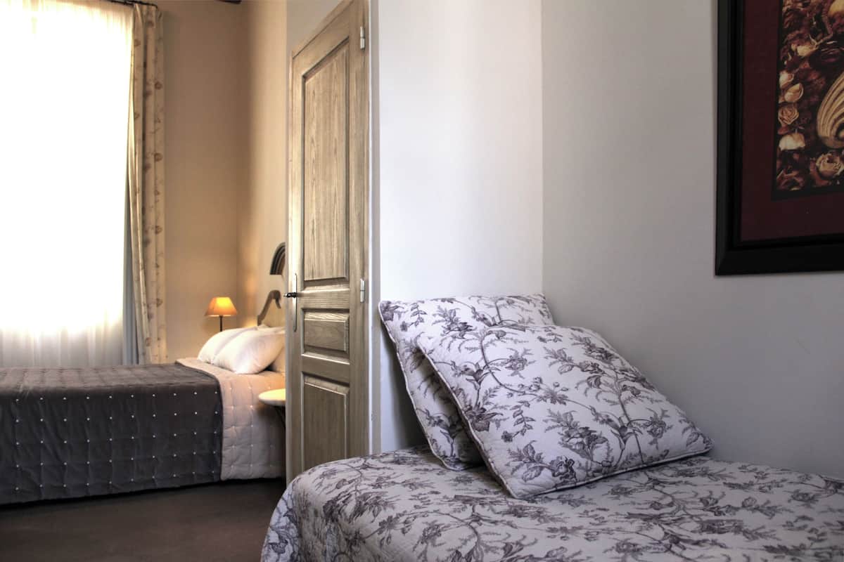 A bedroom with a bed, a bedside table, a lamp, and a door.