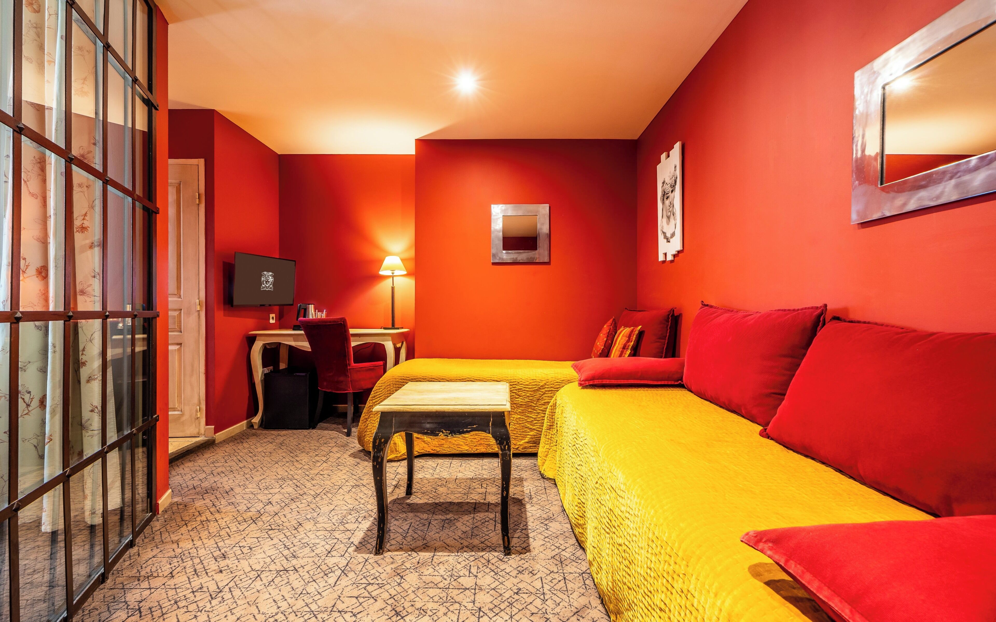A room with a bed, a desk, a chair, a TV, and a lamp.