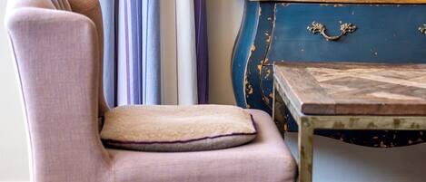 A room with a chair, a small table, a wall-mounted sign, and a patterned rug.
