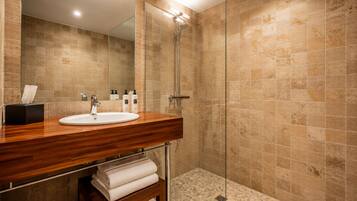 A modern bathroom with a wooden vanity, a glass shower enclosure, and a tiled floor.