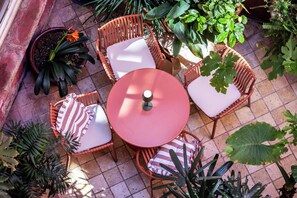 A patio with wicker chairs and a round table, surrounded by potted plants. - Hôtel de l'Amphithéâtre (Arles)
