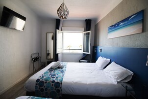 Une chambre d’hôtel avec un lit, une fenêtre, un tableau, une télévision et un porte-serviettes.