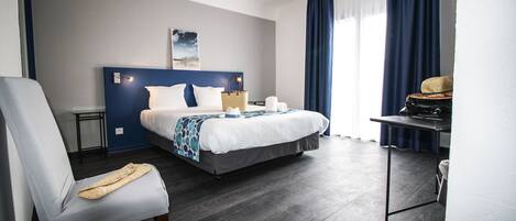 Una habitación de hotel moderna con una cama grande, un escritorio, una silla y vistas al exterior.