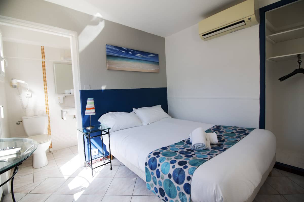 A hotel room with a bed, a bathroom, and a closet.