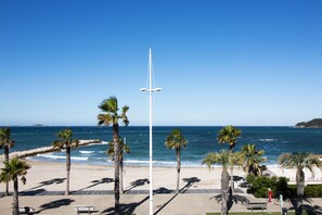 A beach with palm trees, a flagpole, and a bench. - Bel Azur (Six-Fours-les-Plages)