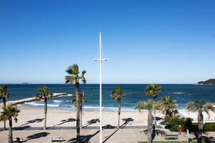 Une plage avec des palmiers, un mât de drapeau et un banc.