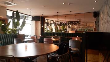 L’intérieur d’un restaurant, avec des banquettes, des tables et un coin bar.