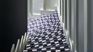 A narrow hallway with a patterned carpet and white walls. - Hotel 10 Opera by HappyCulture (Paris)