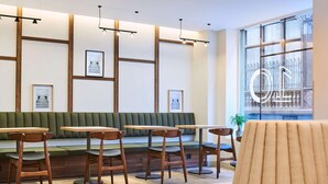 A modern interior with wooden tables and chairs, a green cushioned bench, and framed artwork on the walls. - Hotel 10 Opera by HappyCulture (Paris)