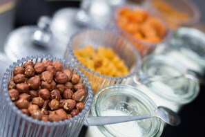 A variety of food items in clear containers, including nuts, dried fruits, and a jar with a spoon.