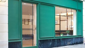 A building facade with large windows and a green trim. - Hotel 10 Opera by HappyCulture (Paris)