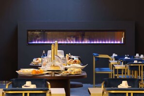 Un espace repas avec un buffet, des chaises recouvertes de tissu bleu et une cheminée en arrière-plan.