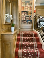 Una escalera con alfombra decorativa y una estantería llena de libros.