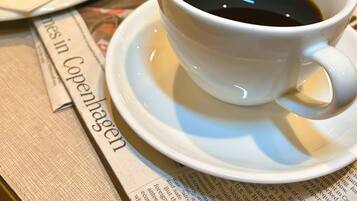 Une table mise pour le petit-déjeuner avec une tasse de café, un croissant, un jus d’orange et un journal.