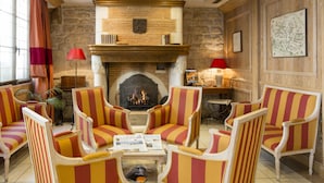 A room with striped armchairs, a fireplace, and a map on the wall. - Hotel Niel (Paris)