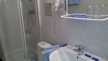 Ein Badezimmer mit Dusche, Toilette, Waschbecken und Handtuchhalter.