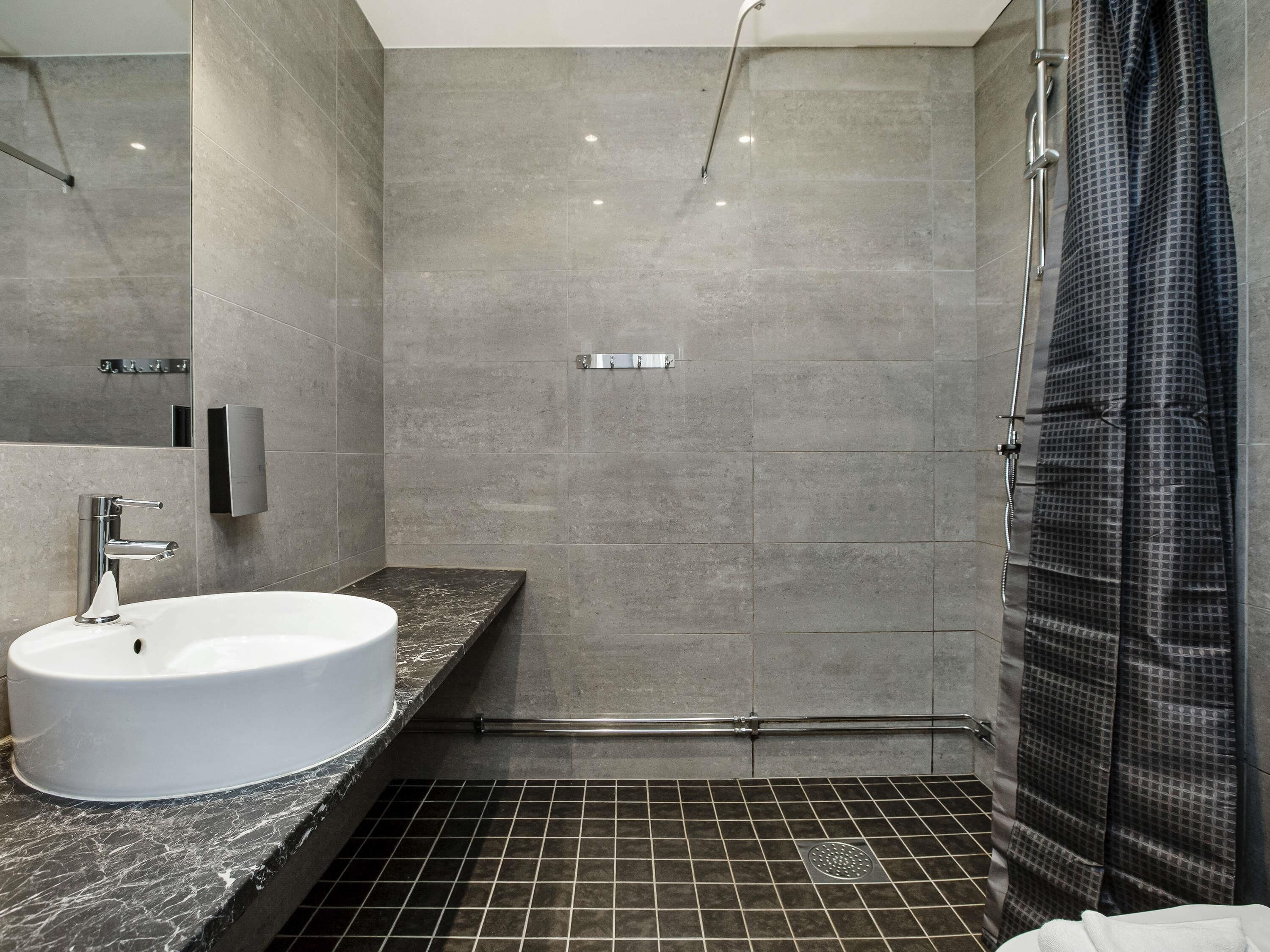 A modern bathroom with a white sink, a shower with a glass door, and a tiled floor.