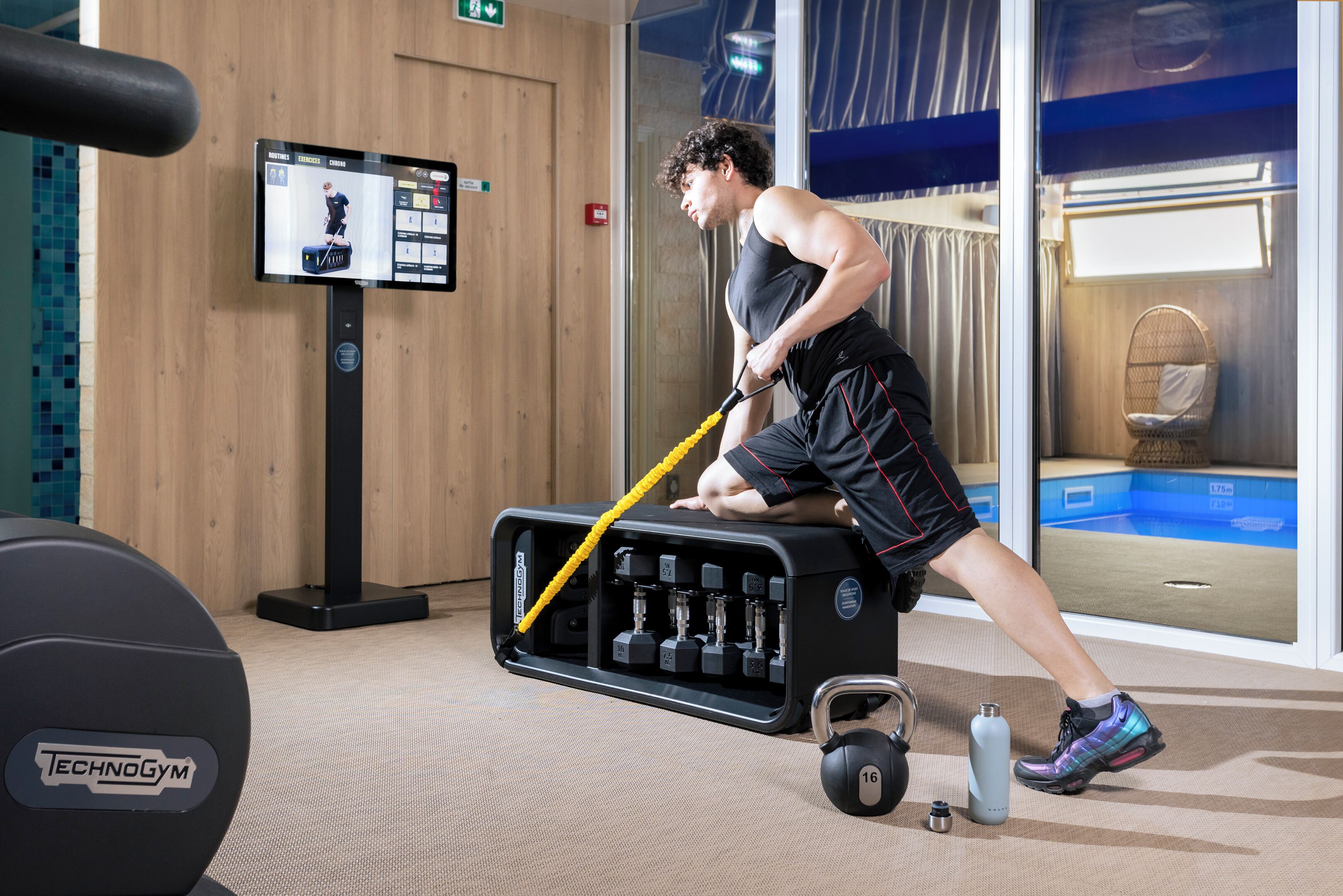 Ein Fitnessraum mit Klimmzugstange, Gewichte und einer Wasserflasche.