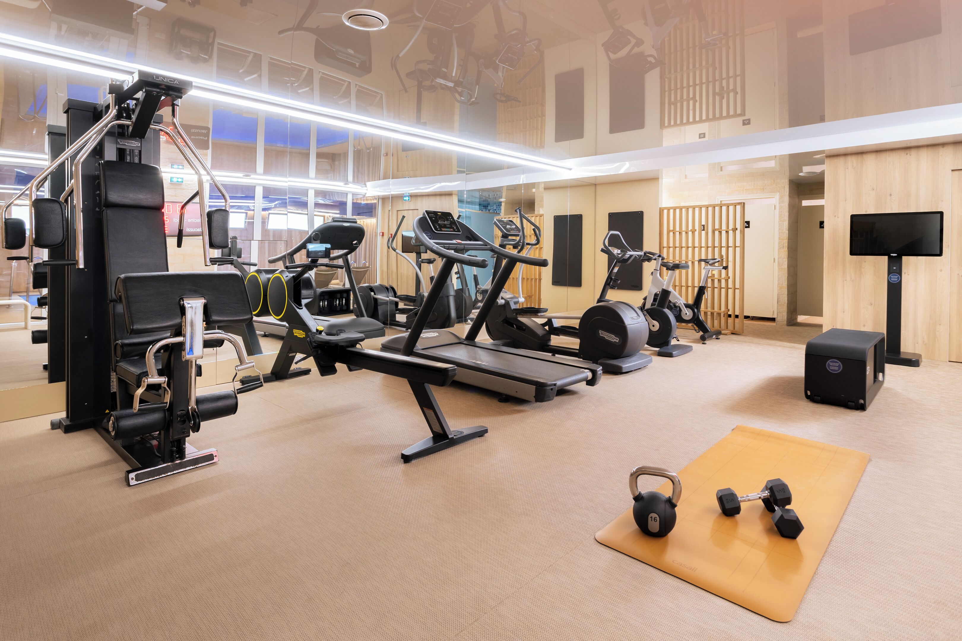 A gym with various exercise equipment, including treadmills, weight machines, and free weights.
