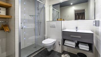 Een moderne badkamer met een glazen douchecabine, toilet, wastafel met kastje en een spiegel.