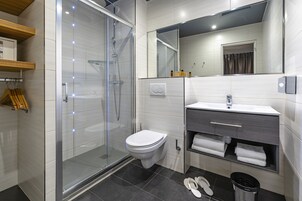 Un baño moderno con cabina de ducha de vidrio, inodoro, lavabo con tocador y espejo.